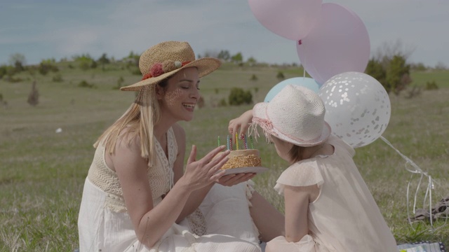 年轻的妈妈和她的小女儿在自然公园用蛋糕和气球庆祝生日-S_LOG2视频下载