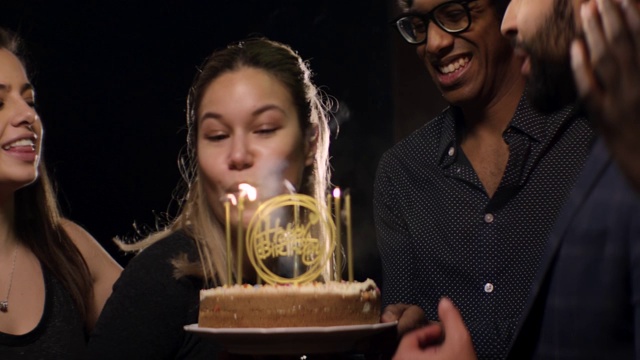 年轻女子吹灭生日蛋糕蜡烛视频素材