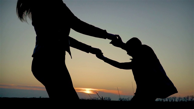 慢镜头母子手牵着手，在傍晚的夕阳中旋转视频下载