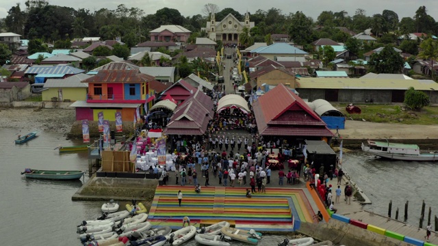 鸟瞰图拍摄的人在城市的街道上狂欢节期间，无人机飞向前从游客之间的结构中Kai群岛，印度尼西亚视频下载