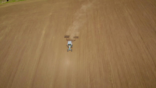 拖拉机和圆盘耙在尘土飞扬的田野上的俯视图视频下载