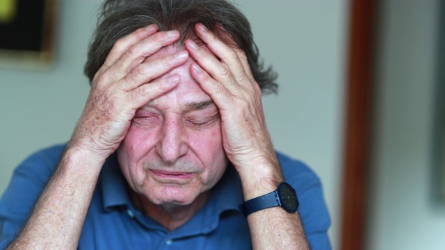 老人用手捂着脸，压力和疲惫的70多岁老人感到压力视频下载