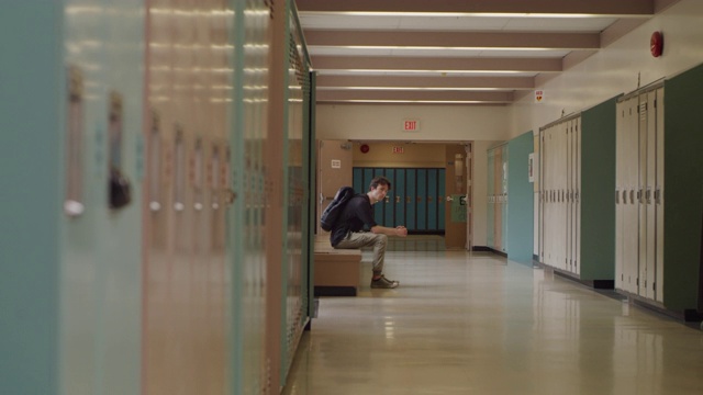 十几岁的学生坐在空荡荡的学校走廊里视频素材
