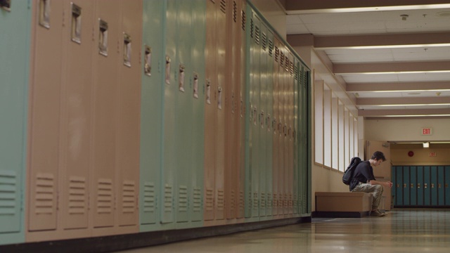 一个十几岁的学生独自坐在学校走廊里视频素材