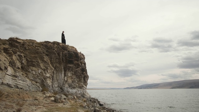 穆斯林女子站在山顶的悬崖边上，大湖视频素材