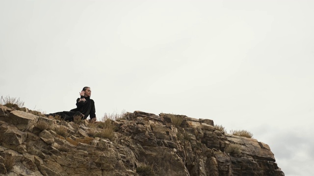穆斯林女子坐在悬崖边上的山顶，大湖视频素材