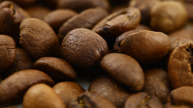咖啡豆被烘烤成棕色，咖啡豆旋转着，慢慢地转着圈，俯视图，特写。视频素材