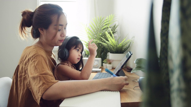 亚裔女儿在家和母亲一起参加网络课程。视频素材