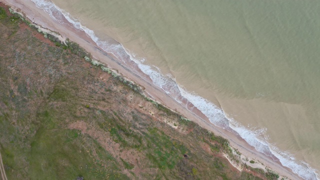 无人机的美丽无缝永不结束的镜头，而绿松石的海浪打破了沙滩的海岸线。航拍的黄金野生海滩遇见深蓝色的海水和泡沫的波浪。自顶向下视图视频下载