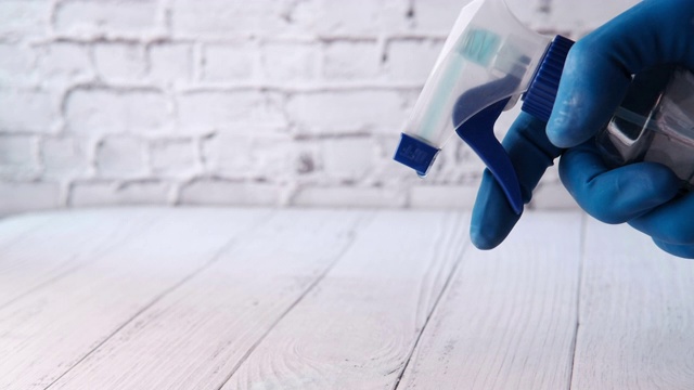 手持喷瓶和清洁桌子的蓝色橡胶手套视频素材
