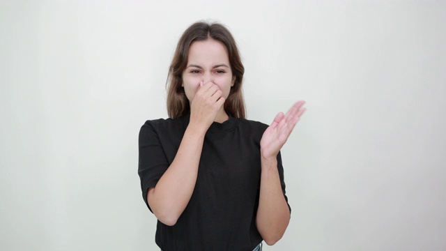 一个女人用手捂着鼻子，因为一股臭味，她做了个鬼脸视频素材