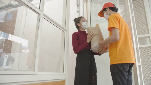 亚洲送货员在冠状病毒隔离期间为亚洲女性顾客送货视频下载