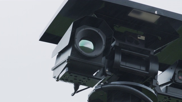 在蓝天的映衬下，一个安装在杆子上的安全摄像头的旋转镜头视频素材