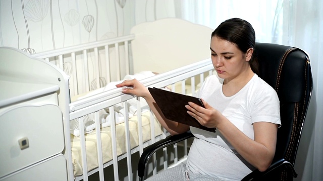 业务在家里。带孩子的母亲在婴儿床附近工作视频素材
