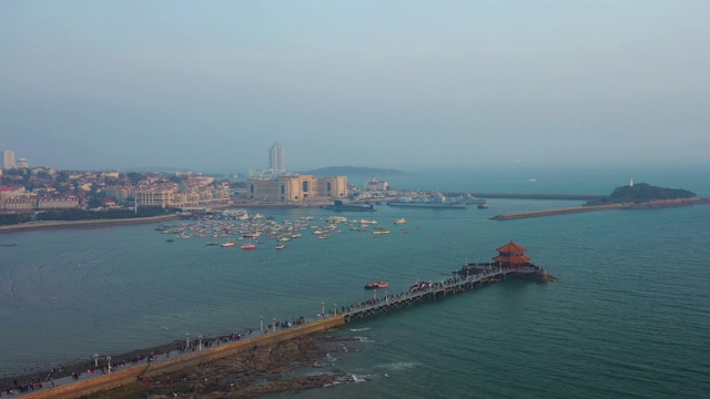 阳光明媚的夜晚青岛著名的海滩湾码头宝塔拥挤的码头航拍全景4k中国视频下载