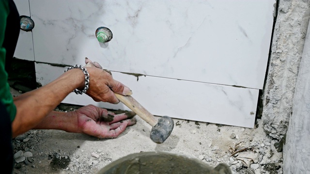 人用锤子在墙上贴大理石瓷砖视频下载