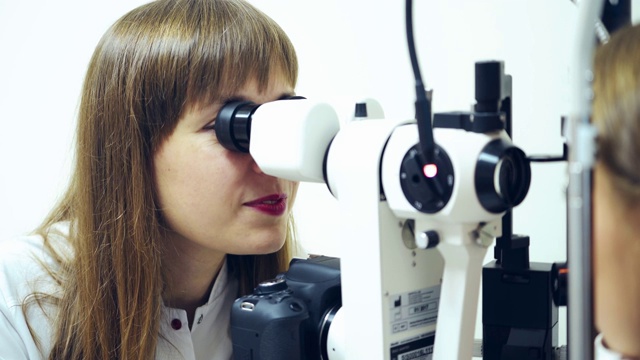 女医生检查病人的眼睛。眼科检查用医疗眼科设备。验光师在临床应用生物显微镜诊断眼睛。视频下载