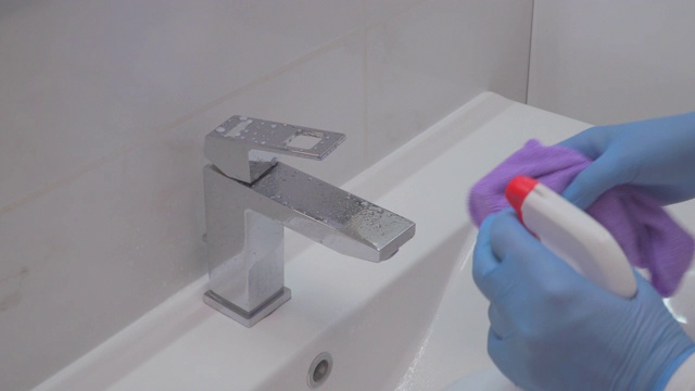 一个女人在给浴室的水槽消毒视频素材