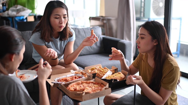3位亚洲华人女性朋友在客厅吃披萨作为午餐视频下载