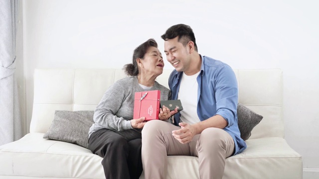 快乐的亚洲人给他的母亲礼物盒庆祝母亲节。视频素材