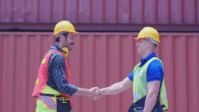 两名技术人员或工程师工人在集装箱工作区域一起讨论然后愉快地握手。具有良好管理体系的工业企业理念视频素材