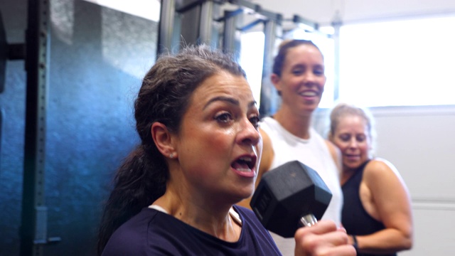 微笑的女人在健身课上和朋友们用哑铃唱歌视频素材