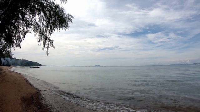 视频从左到右，海浪拍打着海滩，背景是海中的树和泰国甲米的云。视频下载