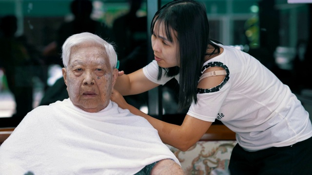 女性在家里用剪子剪奶奶的头发视频素材