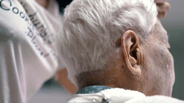 冠状病毒隔离:在家里给孙女剪头发的老年妇女视频素材