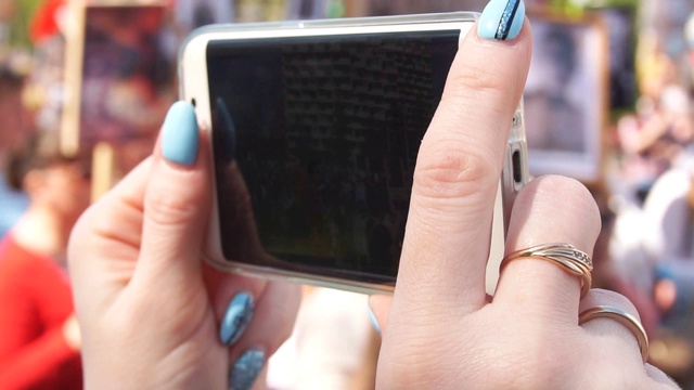 在庆祝胜利日期间，女人的手在手机上做一个视频的特写视频素材