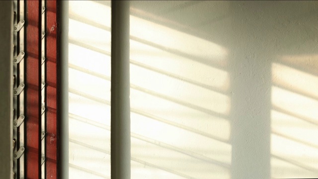 时间流逝:阳光透过百叶窗照到白色的混凝土墙壁上。视频素材