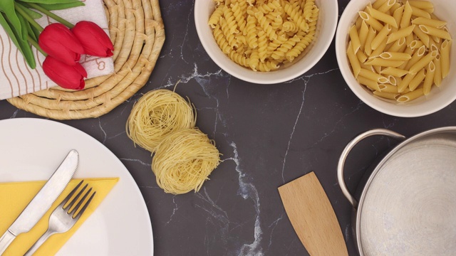 厨房用具，白色碗中的意大利面和红色郁金香出现在黑色大理石背景上-停止运动视频素材