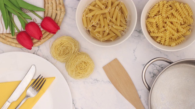 意大利面和厨房用具出现在大理石桌子上三朵红色郁金香-停止运动视频素材