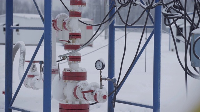 工业油电动离心泵在油田冬季与钻井平台一起工作，抽送原油作为化石燃料能源。井口连接油井设备。视频素材