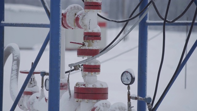 工业用油泵设备在油田冬季与钻井平台一起工作，为化石燃料能源抽送原油。井口连接油井设备。视频素材