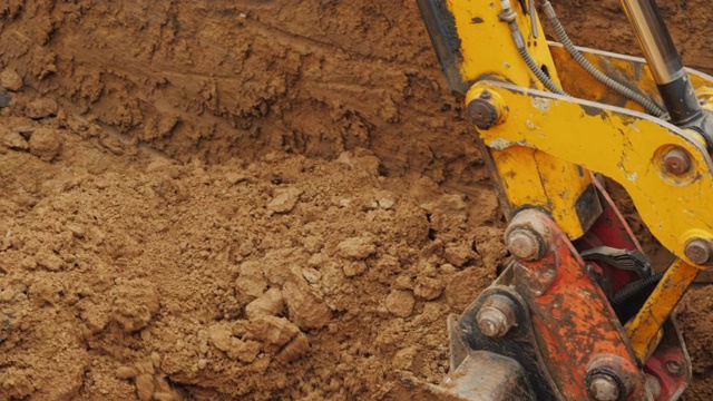 建筑工地的土方设备。挖掘机用铲斗从沟里挖出地面视频下载