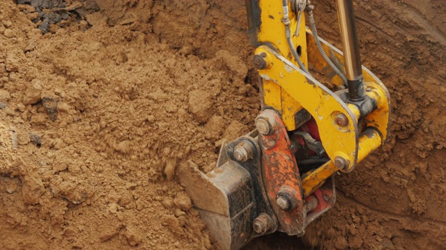 一个强大的挖掘机的铲斗从坑中清除泥土，铺设管道视频素材