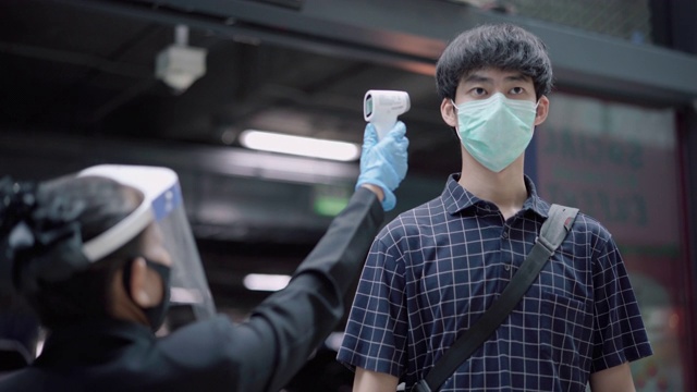 耐心的亚洲男人用体温计测脸和手的温度视频下载