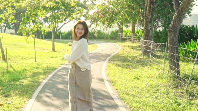 慢动作的快乐年轻美丽的亚洲女人在公园里散步和跳跃，享受与大自然在春天的傍晚。微笑漂亮的女孩放松和玩在暑假。视频素材