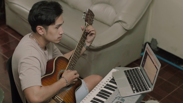 亚洲男子学习弹吉他在家库存视频视频素材