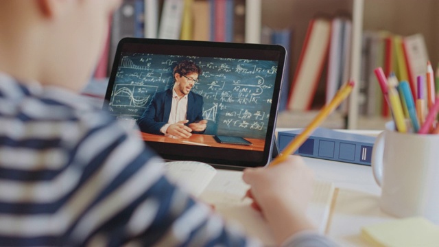聪明的小男孩用数码平板电脑与他的老师视频通话。屏幕显示在线讲座与教师解释从教室的主题。电子教育、远程教育、家庭教育视频下载
