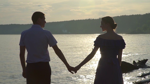 男人和女人在海滩上的日落手牵手视频素材