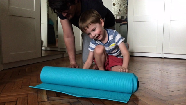 父亲和孩子在家里铺开垫子准备锻炼视频素材