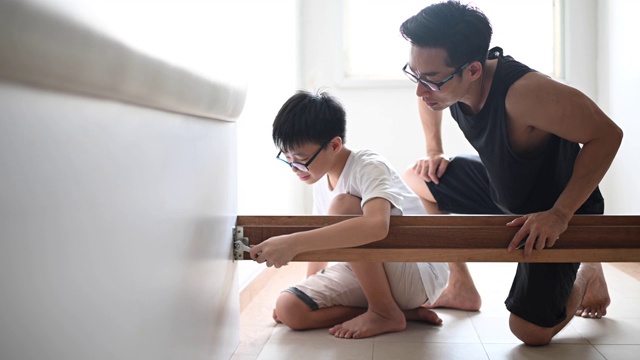 一个亚裔华人家庭搬家父子组装床架视频素材