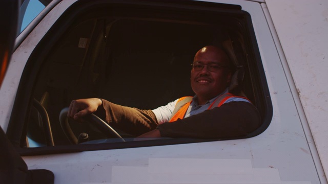 快乐的卡车司机在驾驶室里对着镜头微笑视频下载