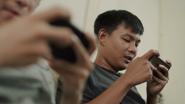 亚洲男人在客厅里和朋友玩电子游戏视频素材