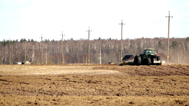 农业综合企业，农民在他的土地上开始春季的农业工作时，用拖拉机耙土视频下载