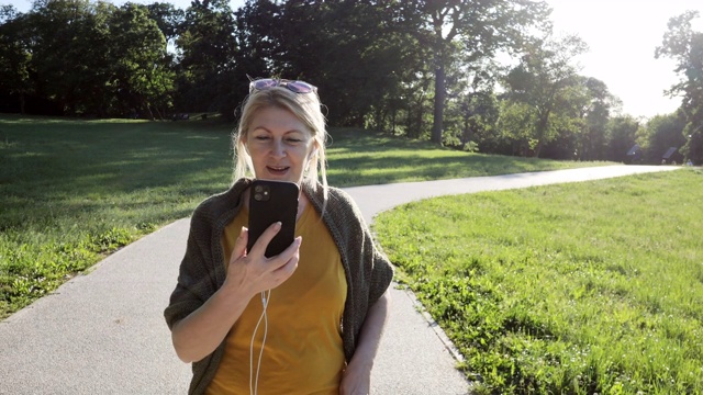 老妇人在春日户外公园用手机进行视频通话——慢动作视频视频素材