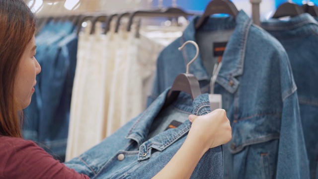 在服装店的衣架上挑选衣服的女人视频素材