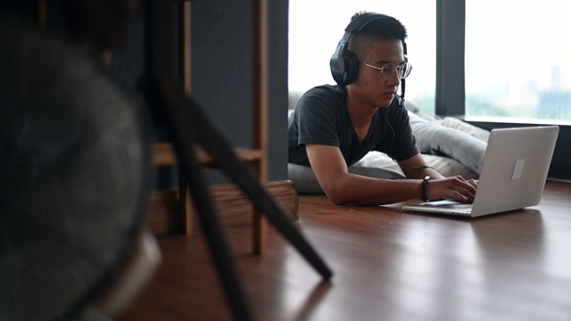 一个亚洲的中国少年男孩在家上学，在卧室里用笔记本电脑学习视频素材